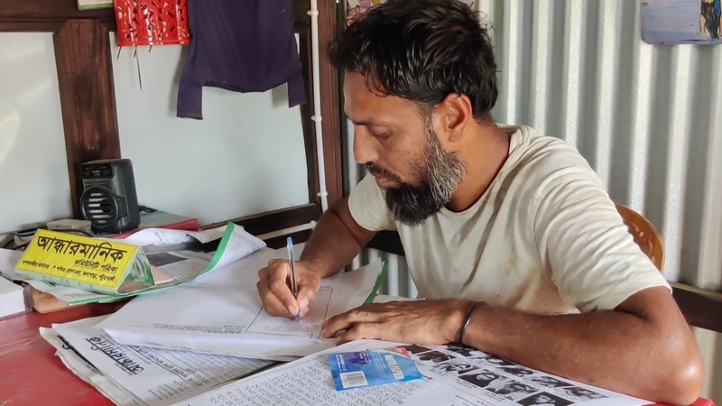 "Hassan Parvez, a dedicated day laborer from West Sonatala village, proudly holds a copy of his handwritten newspaper named after the Andharmanik River." Photo: V7N